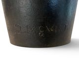 a black pot with a handle on a white surface