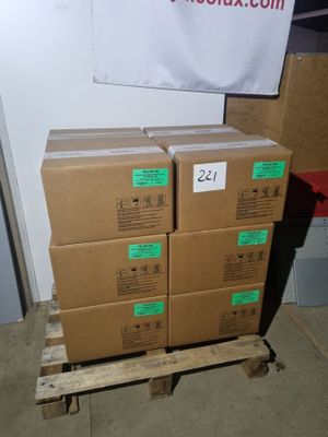 Plusieurs cartons sont empilés sur une palette devant un panneau