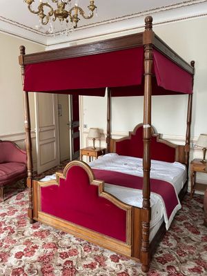 a four poster bed in a room with a chandelier