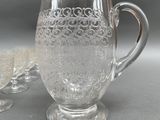 a glass pitcher with a handle next to a glass of wine