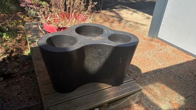 un porte-gobelet en plastique noir posé sur un banc en bois