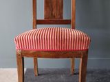 une image représentant une chaise en bois dont l'assise est recouverte d'un tissu rayé rouge et blanc