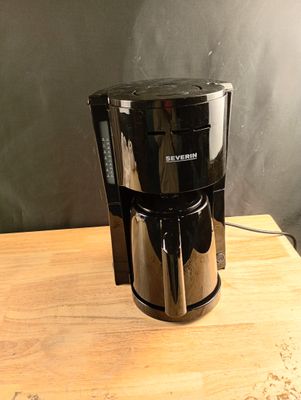 une cafetière noire posée sur une table en bois