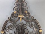 a decorative iron wall hanging on the wall next to a pair of candles