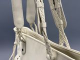 un sac à main blanc avec une anse tressée sur fond bleu