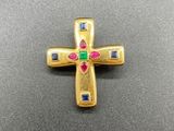 une image représentant une croix en or ornée de pierres multicolores