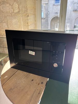un micro-ondes posé sur une table devant une fenêtre