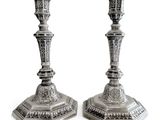 deux chandeliers en argent posés sur une surface blanche