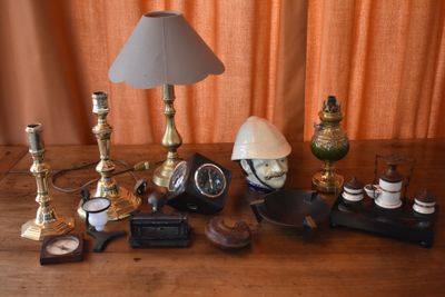 a table with a lamp, a clock, a clock and other items on it