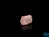 a pink diamond on a black surface with a black background