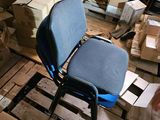 une chaise bleue posée dans une pièce remplie de cartons