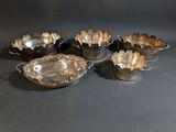 four silver plated bowls with handles and handles on a black surface