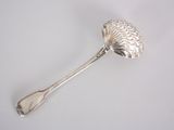 a silver spoon with a leaf on it on a white surface