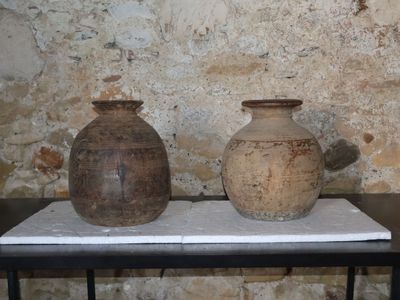 deux vases posés sur une table devant un mur de pierre