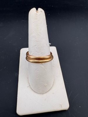 un gros plan d'une bague en or posée sur un présentoir à bagues blanc
