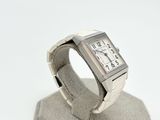a silver watch sitting on a stand on a white surface