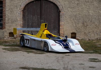 une voiture de course jaune et blanche garée devant un immeuble