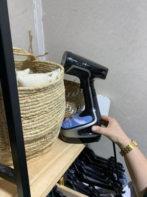 quelqu'un utilise un sèche-cheveux pour sécher des vêtements posés sur une étagère