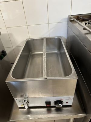 une grande friteuse en acier inoxydable trônant au milieu d'une cuisine