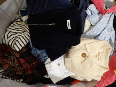 a pile of clothes that is sitting on a bed