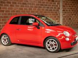 a small red car parked in front of a brick wall