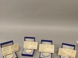 four different types of silver coins in boxes on a table