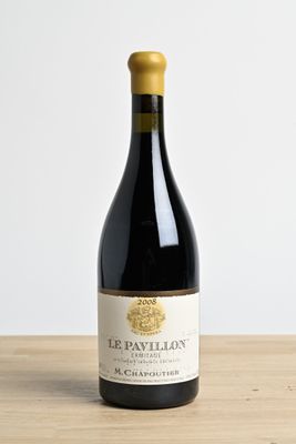 the bottle of wine is sitting on a wooden table