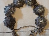 bracelet plaqué argent orné de breloques, posé sur un morceau de papier