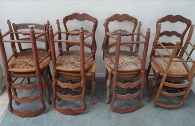 six chaises en bois sont alignées contre un mur blanc
