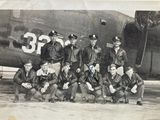 an old black and white photo of a group of men in front of an airplane