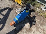a blue machine that is laying on the ground next to a fence