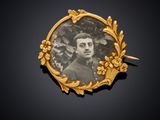 une photo ancienne représentant un homme, dans un cadre doré orné de fleurs