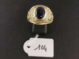 a gold ring with a blue stone sits on a black surface