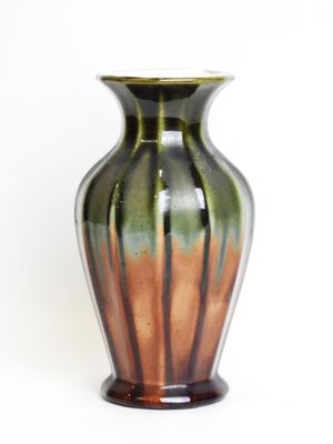 a green and brown vase sitting on a white surface
