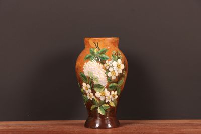 un vase avec des fleurs peintes dessus, posé sur une table