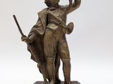statue en bronze représentant un homme tenant un oiseau, avec un autre oiseau posé sur un socle en bois