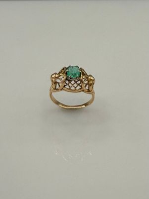 gros plan d'une bague en or avec une pierre verte