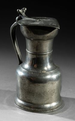 an old silver pitcher sitting on top of a table next to a black background