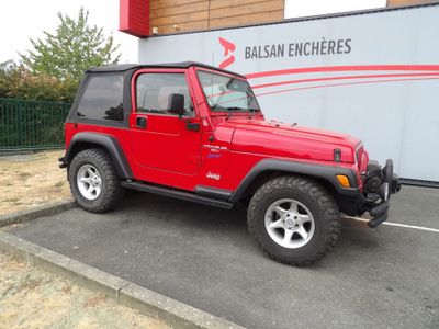 une jeep rouge garée devant un immeuble