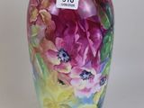 un vase avec des fleurs peintes dessus, posé sur une table