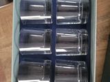 six empty glasses in a box on a table