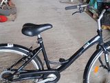 un vélo noir garé dans un garage, avec un panier à l'arrière