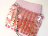 a pink purse with a chain around it on a table