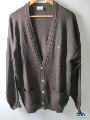 brown cardigan sweater hanging on a hanger against a white wall