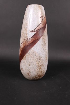 un vase orné d'une plume, posé sur une table