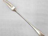a silverware fork with a long handle on a white surface