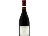 a bottle of red wine sitting on top of a white table