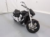 une moto noire garée dans une pièce aux murs blancs