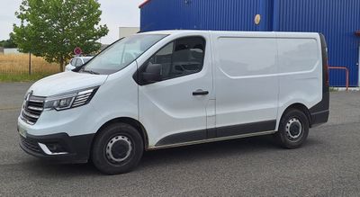 une camionnette blanche garée devant un bâtiment bleu
