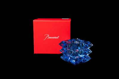 figurine d'ange en verre bleu dans une boîte rouge sur fond noir